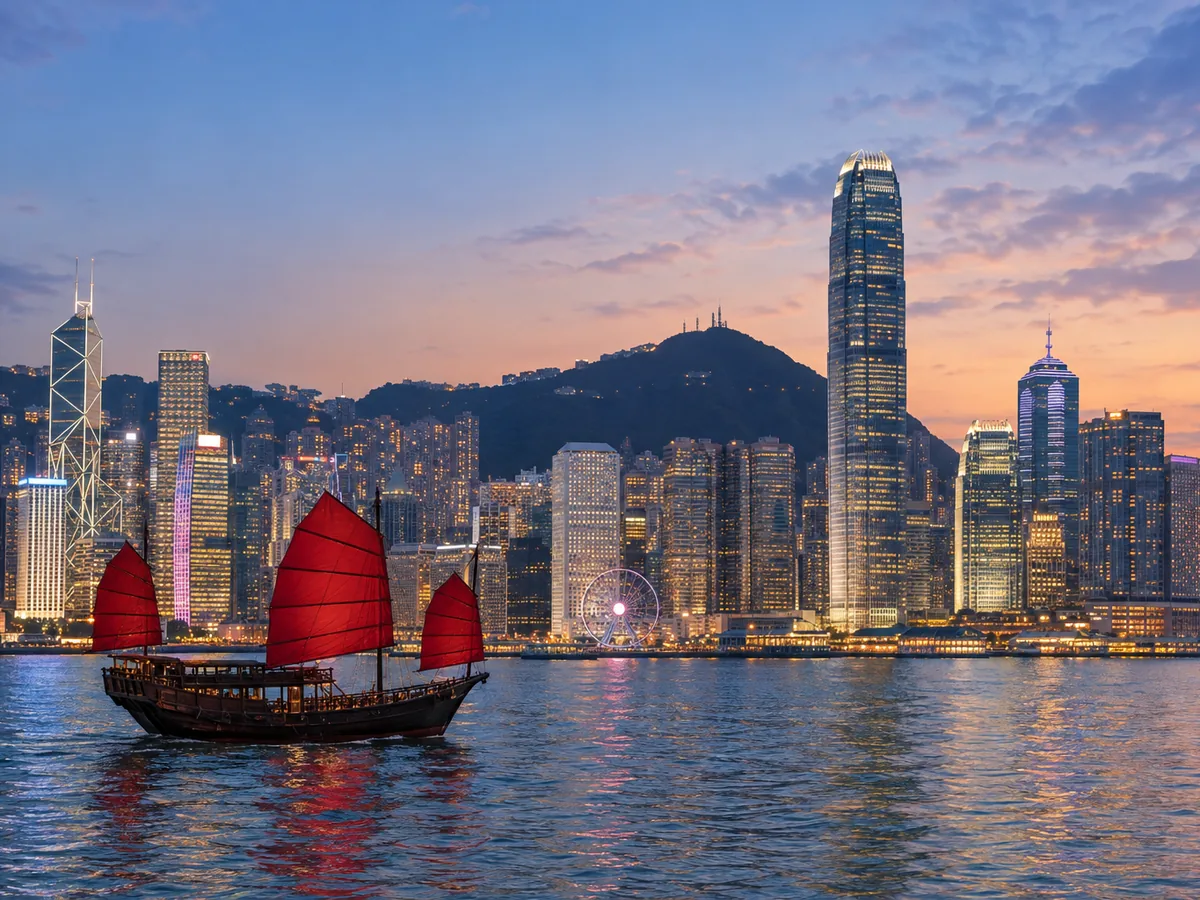 Victoria Harbour and the Hong Kong skyline with a red-sailed junk at blue hour